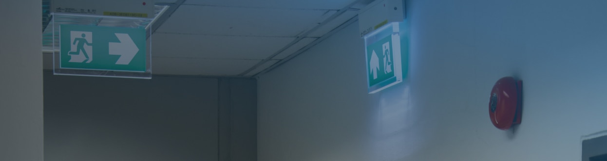 A green sign pointing to an emergency exit in a building